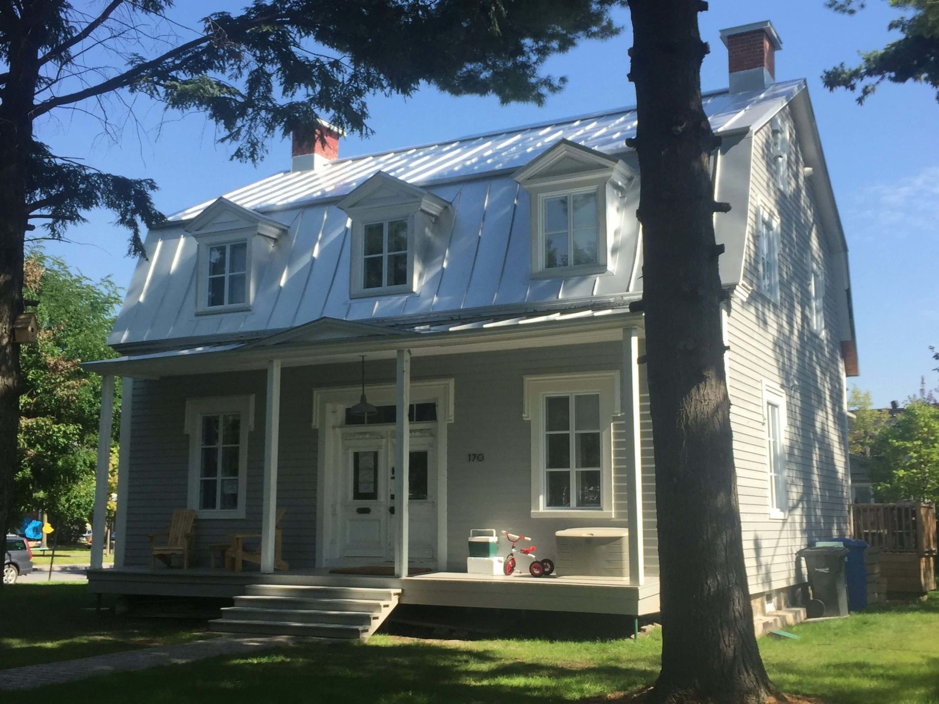 Maison québécoise ancestrale avec toiture à pincette en métal blanc